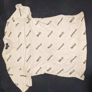 White "paranoid" shirt sleeve shirt with foreign lettering in black.